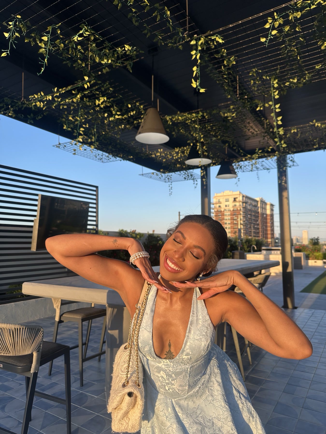 Iyana Admasu laughing on a sunlit rooftop patio in a white dress