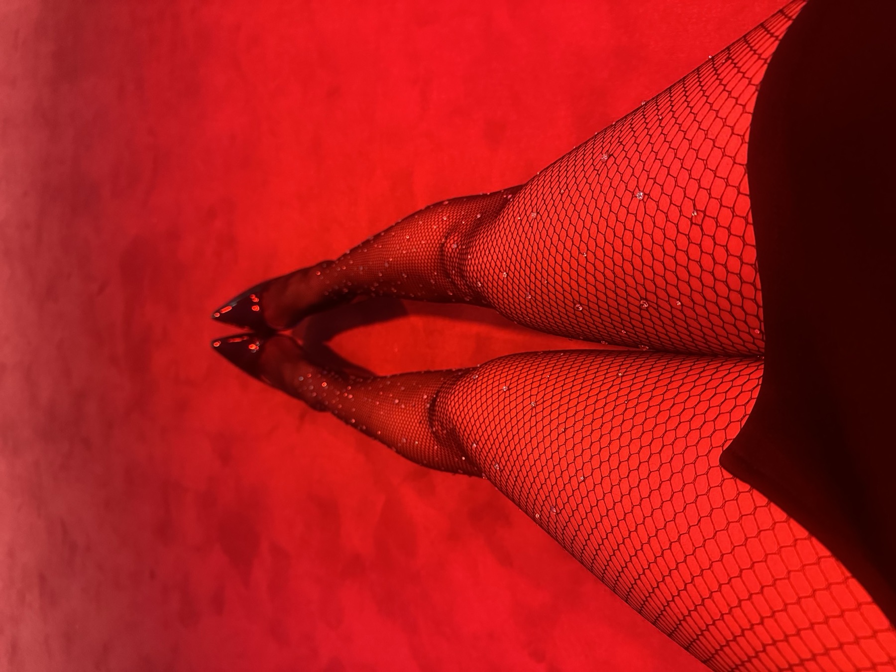 Editorial detail shot of glittered fishnet tights against a red backdrop